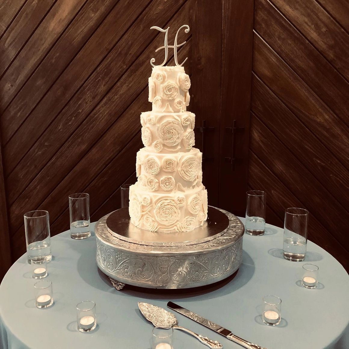 Four-tier white wedding cake with rosette pattern and monogram topper
